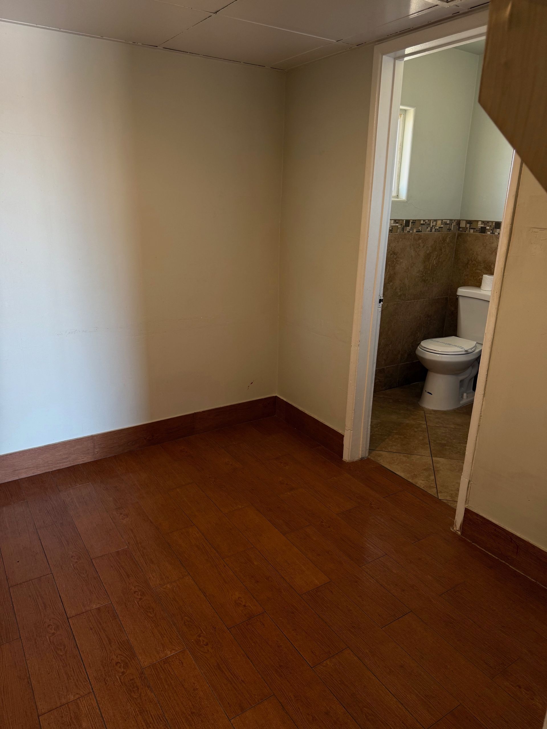 An empty room with a toilet and stairs leading to a bathroom.