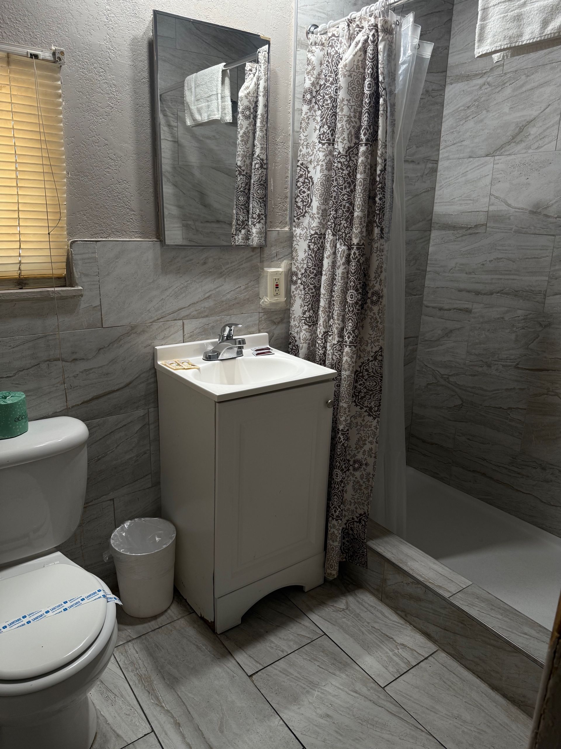 A bathroom with a toilet , sink , mirror and shower.