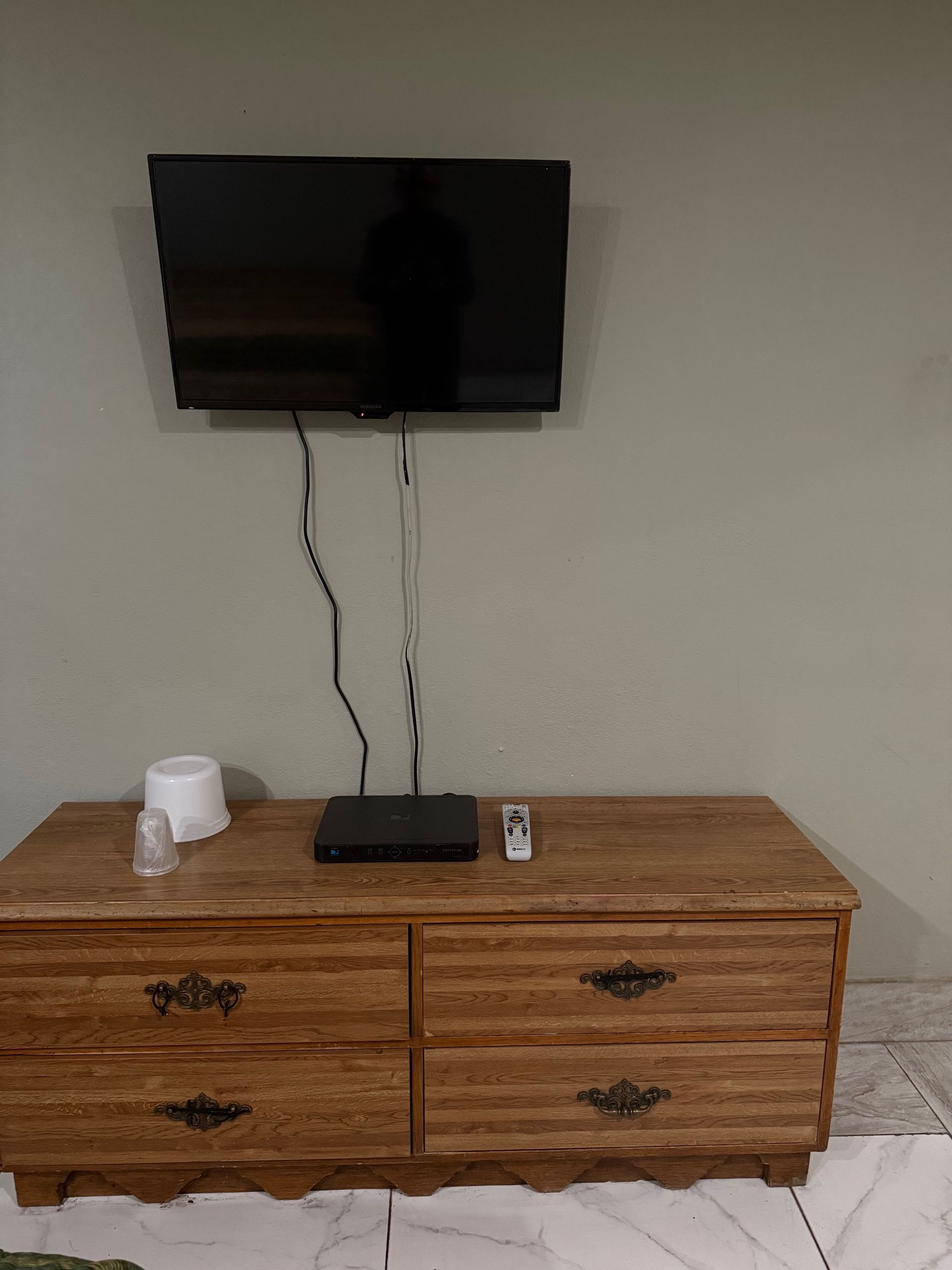 A flat screen tv is mounted to the wall above a wooden dresser