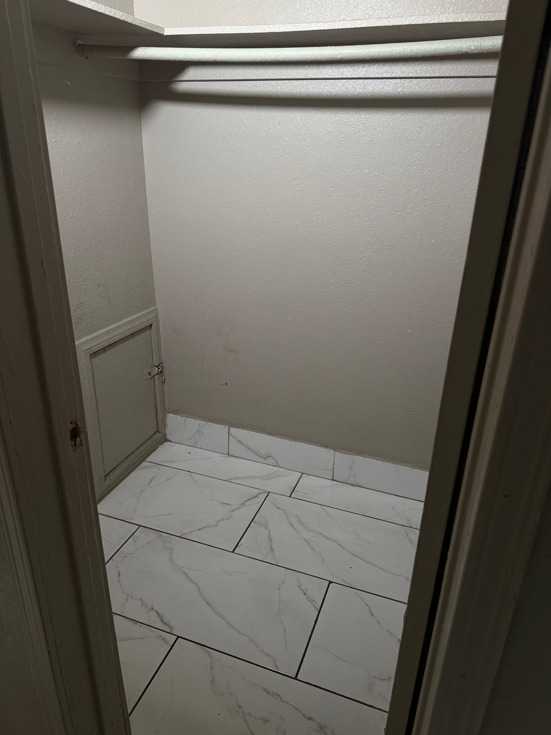 A walk in closet with white tile floors and shelves.