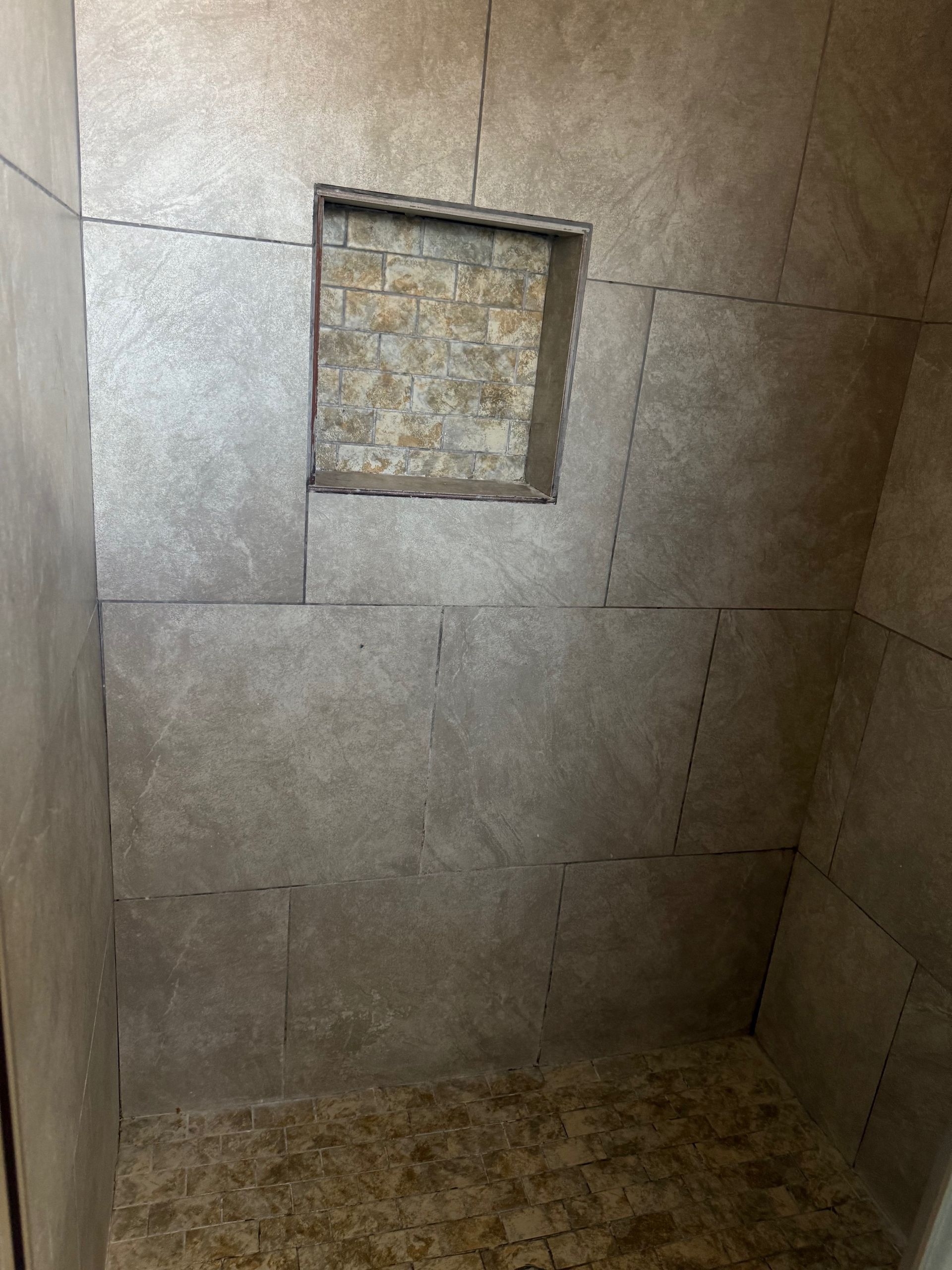 A shower stall with a niche in the wall.