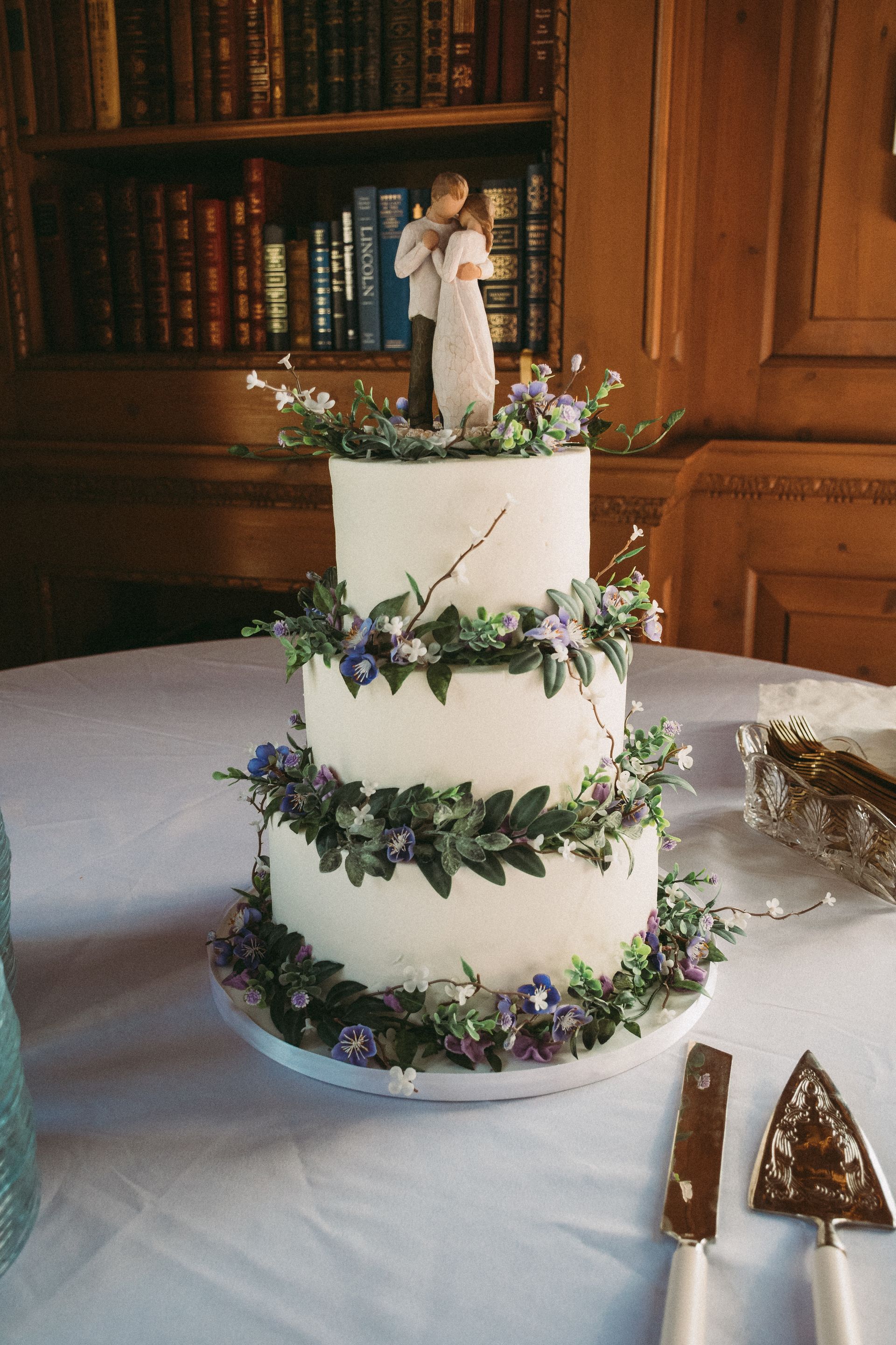 A wedding cake with a figurine of a bride and groom on top is on a table.