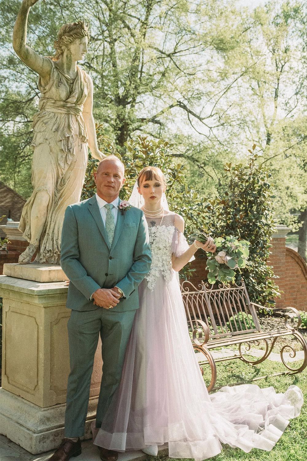 A bride and groom are posing for a picture in front of a statue.
