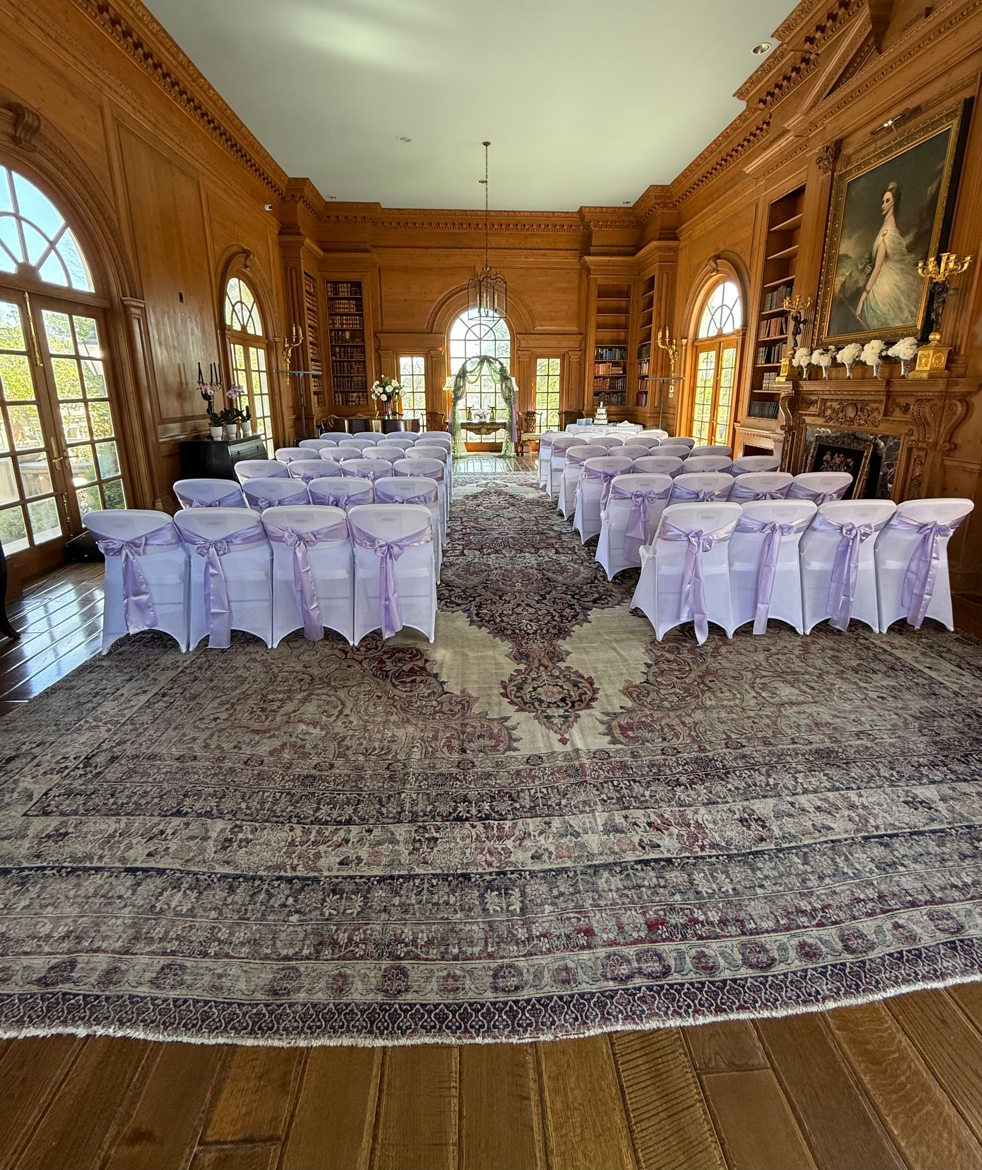 A large room with a lot of chairs and tables set up for a wedding ceremony.