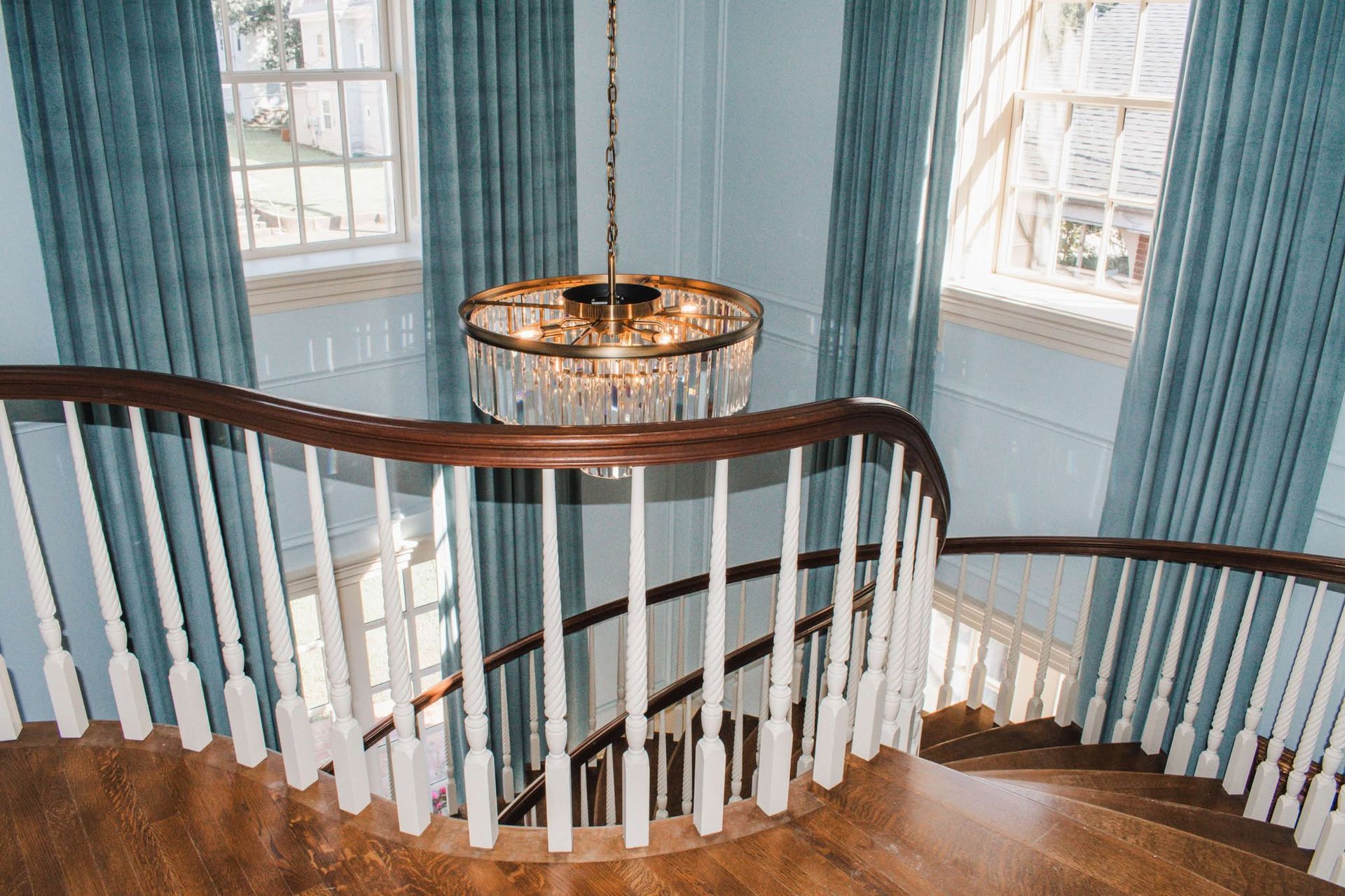 A spiral staircase with a chandelier hanging from the ceiling.