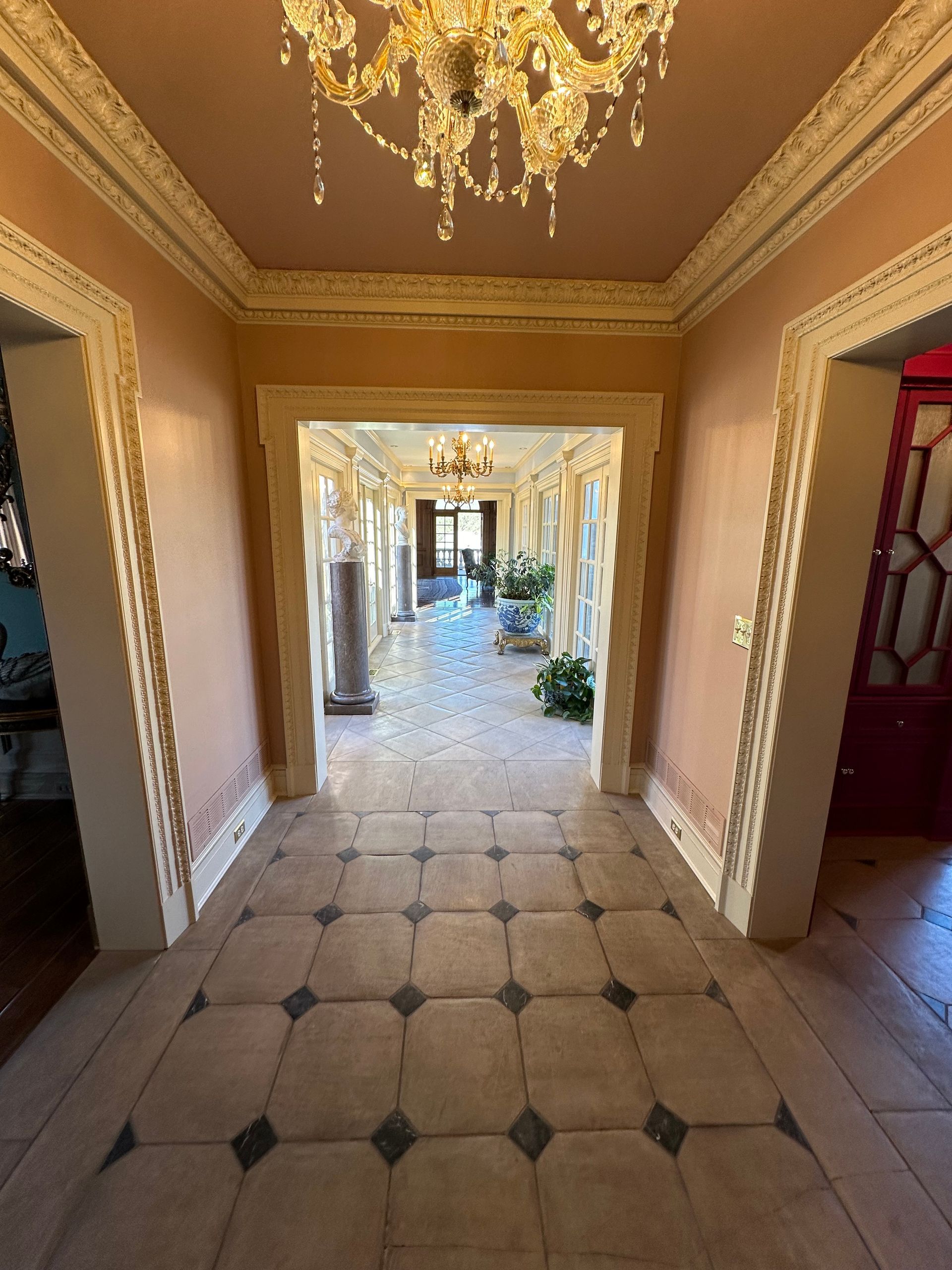 A long hallway with a chandelier hanging from the ceiling.