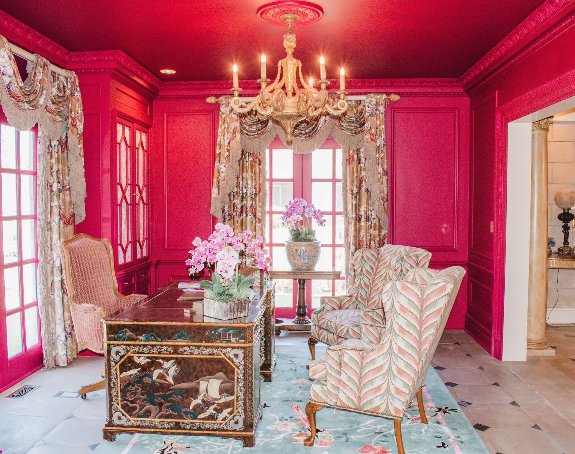 A living room with pink walls and a chandelier.