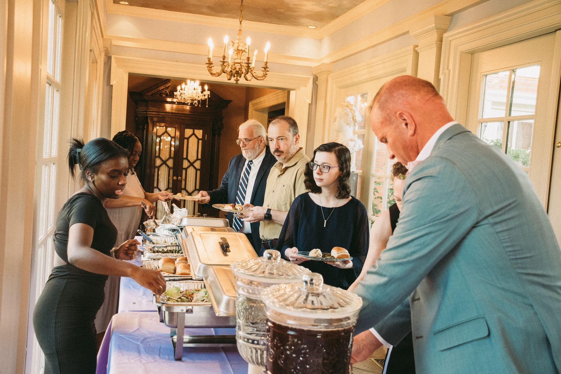 A group of people are standing around a buffet table.