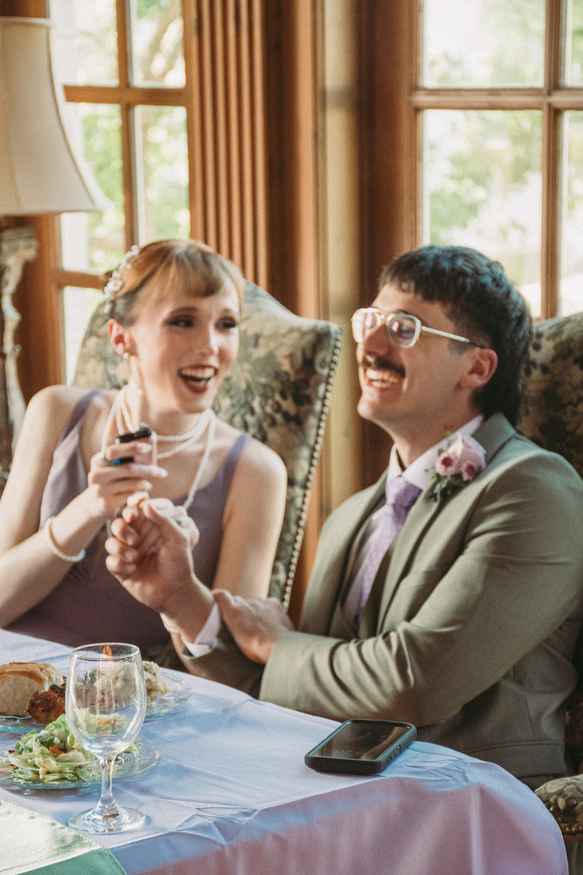 A man and a woman are sitting at a table holding hands and drinking wine.