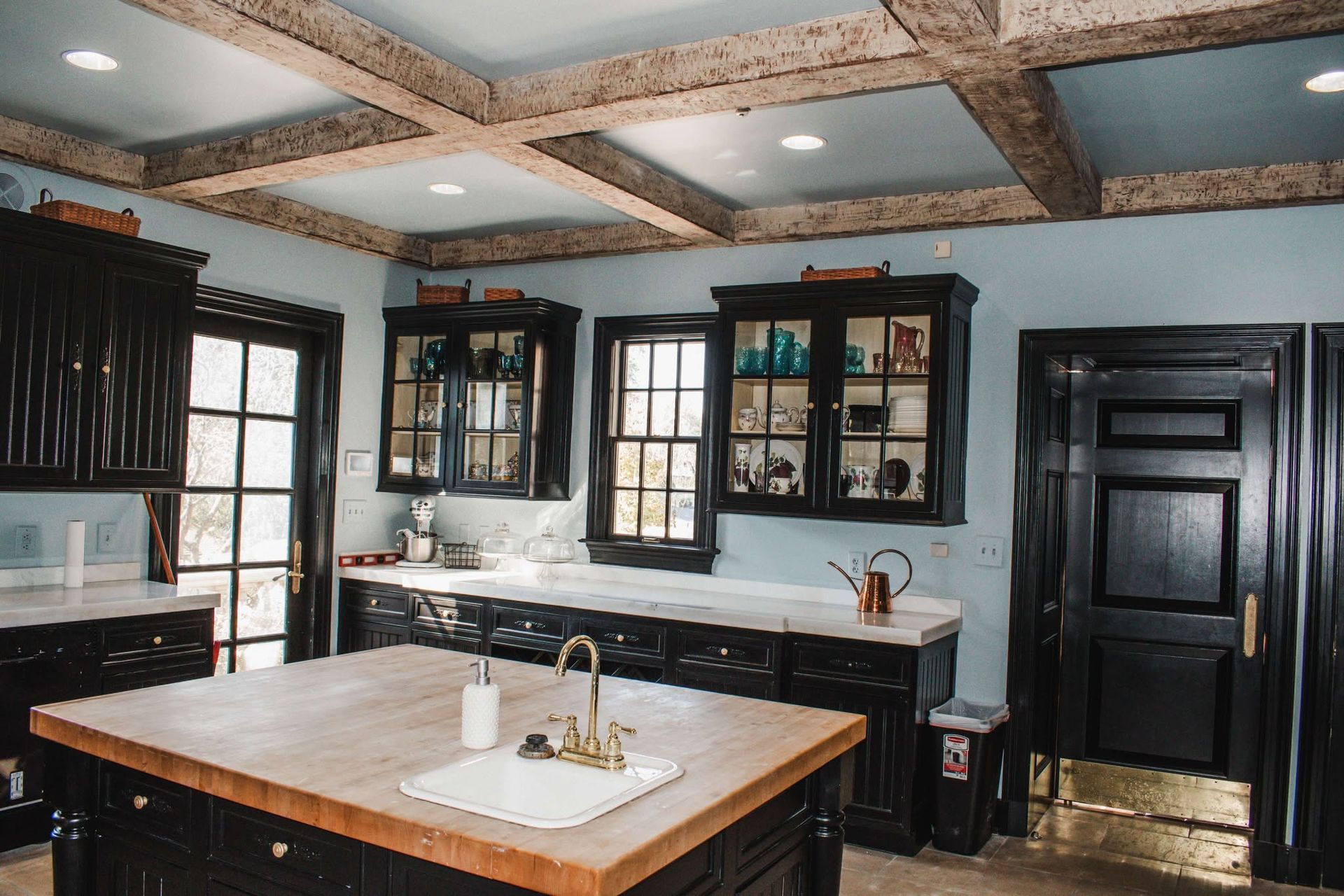 A kitchen with black cabinets , a sink , and a large island.