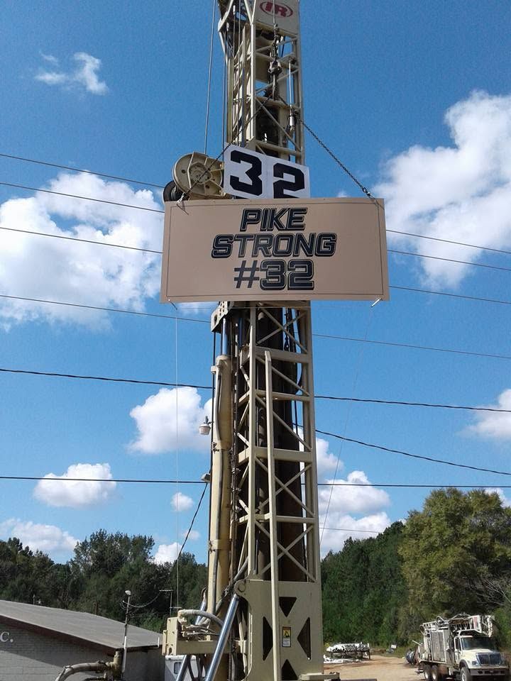 Tower sign reading “PIKE STRONG #32” against a blue sky with clouds
