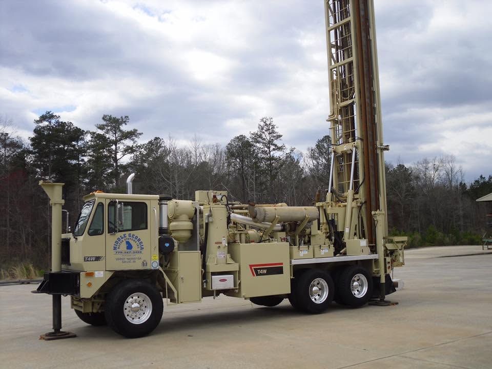 Yellow drilling rig truck parked outdoors under cloudy sky