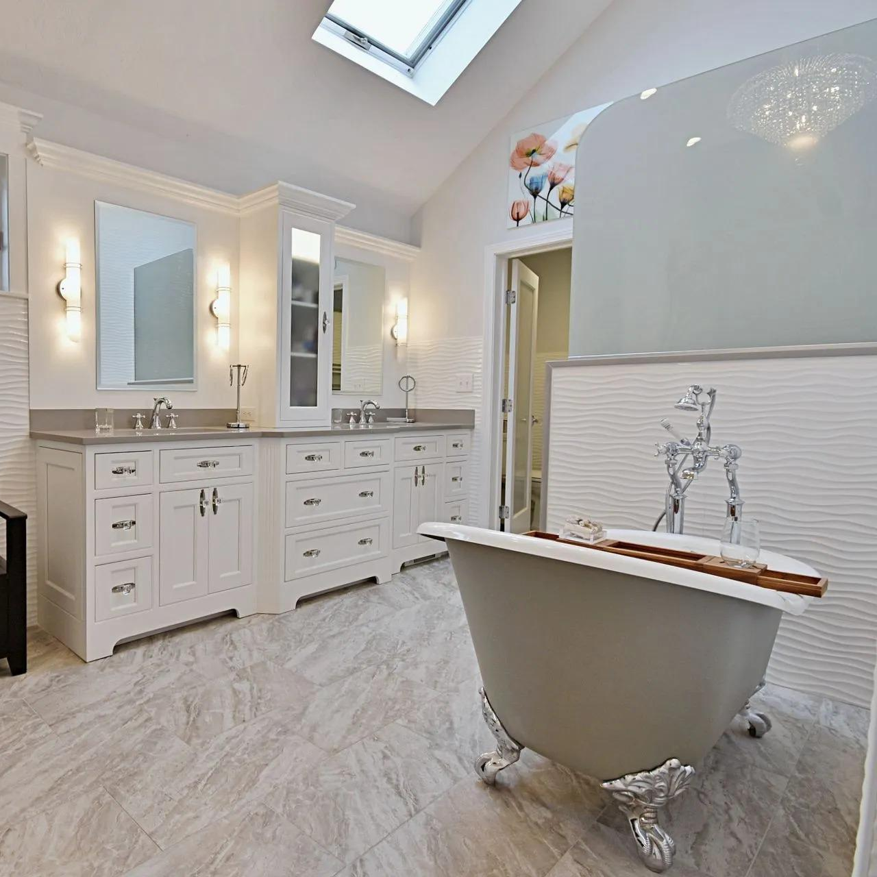 Bright, luxurious bathroom with a gray clawfoot tub, white cabinetry, and a skylight.