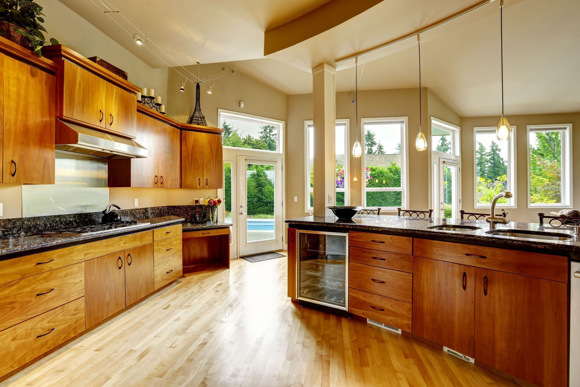 Spacious kitchen with wood cabinets, granite countertops, and large windows overlooking a pool.