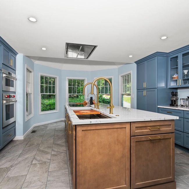 Bright kitchen with blue cabinets, central island, large windows, and wood flooring