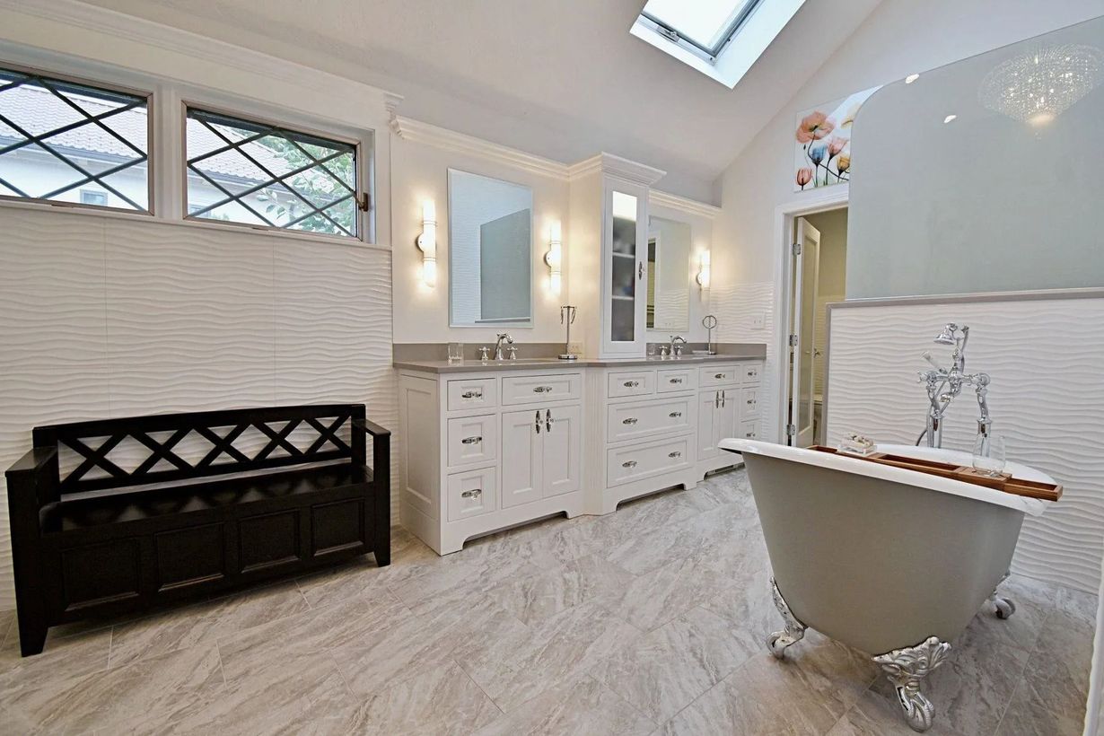Bathroom with white cabinets, a clawfoot tub, and a decorative window.