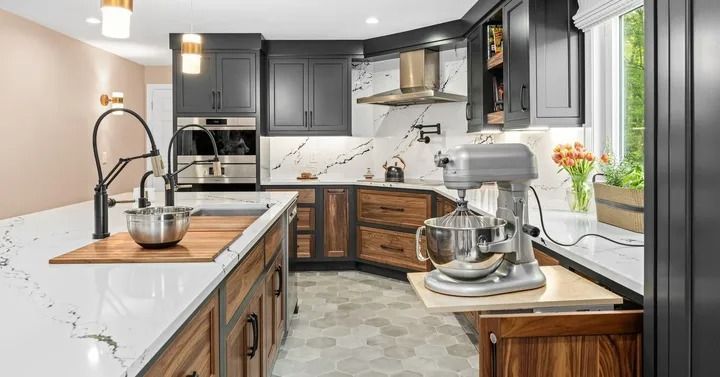 Modern kitchen with dark cabinetry, wood accents, and marble countertops; a stand mixer is on a pull-out shelf.