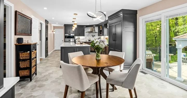 Modern kitchen with gray cabinets, white island, round dining table, and large window.