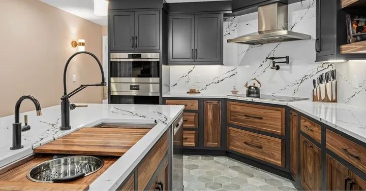 Modern kitchen with dark gray and wood cabinets, white countertops, and stainless steel appliances.