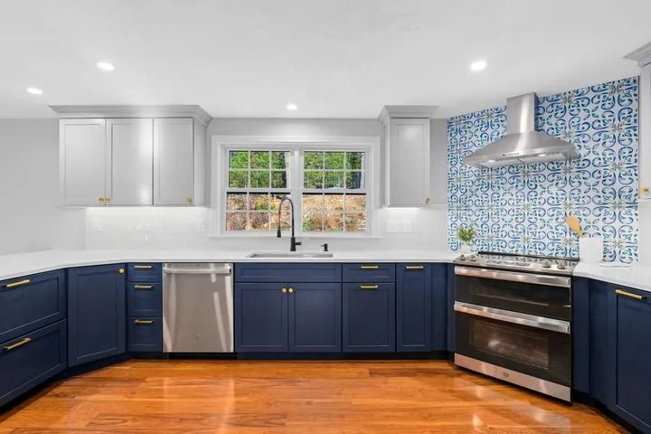 Blue and white kitchen with stainless steel appliances, hardwood floors, and patterned backsplash.