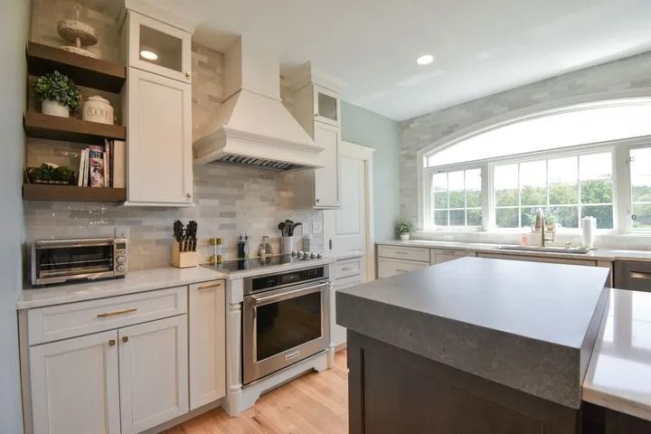 Modern kitchen with white cabinets, stainless steel appliances, and a gray island.