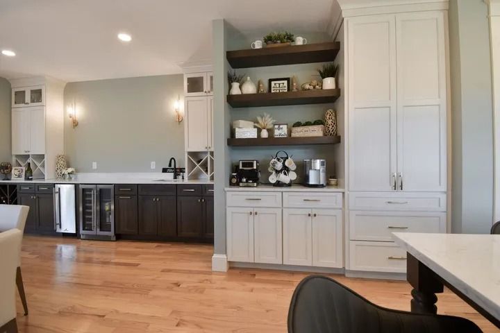 Coffee bar with white and dark cabinets, open shelving, and appliances in a modern kitchen.