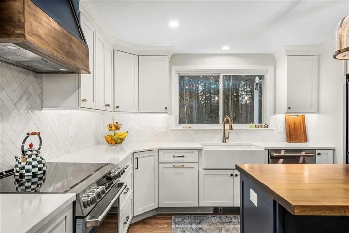 Bright white kitchen with white cabinets, wood accents, and a large window.