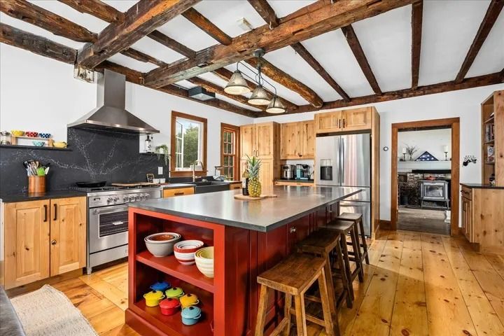 Rustic kitchen with wooden beams, island, stainless steel appliances, and wood cabinetry.