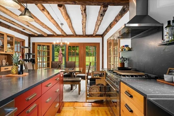 Kitchen with exposed beams, red island, wood cabinets, and French doors to a yard.