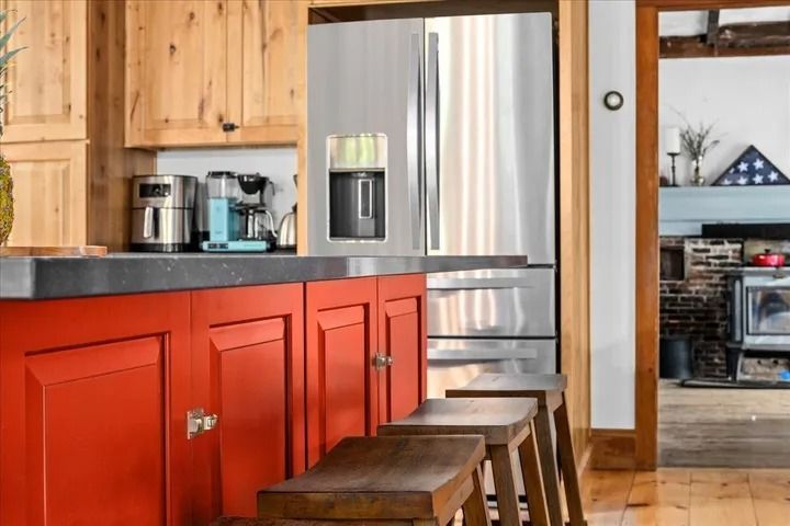 Red kitchen cabinets with wooden stools and a stainless steel refrigerator.