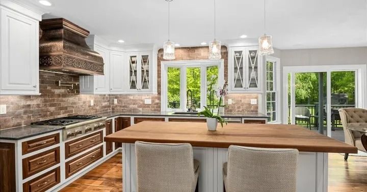 Kitchen with white cabinets, dark wood island, and a window overlooking greenery.