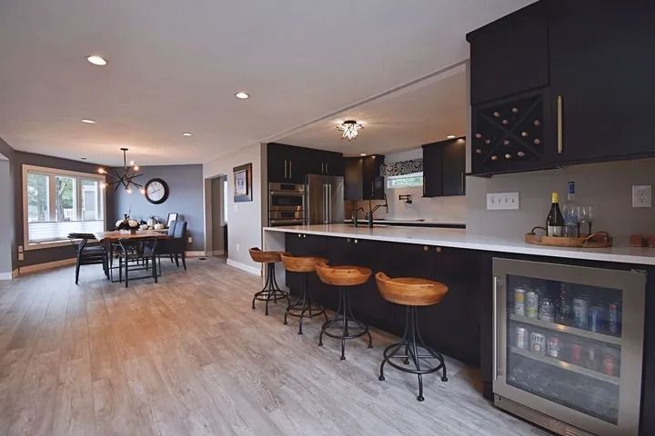Open-concept kitchen and dining area with black cabinets, white countertops, and wood flooring.