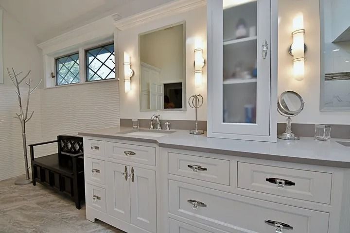 White bathroom vanity with gray countertop, mirror, and cabinet.