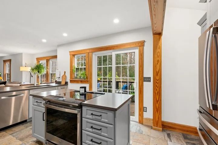 Kitchen with island and stainless steel appliances, sliding door to backyard.