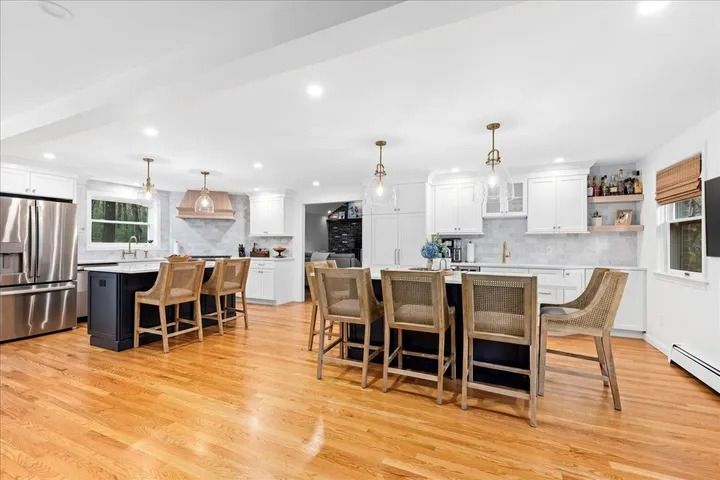 Spacious kitchen with two large islands, white cabinets, stainless steel appliances, and wood flooring.