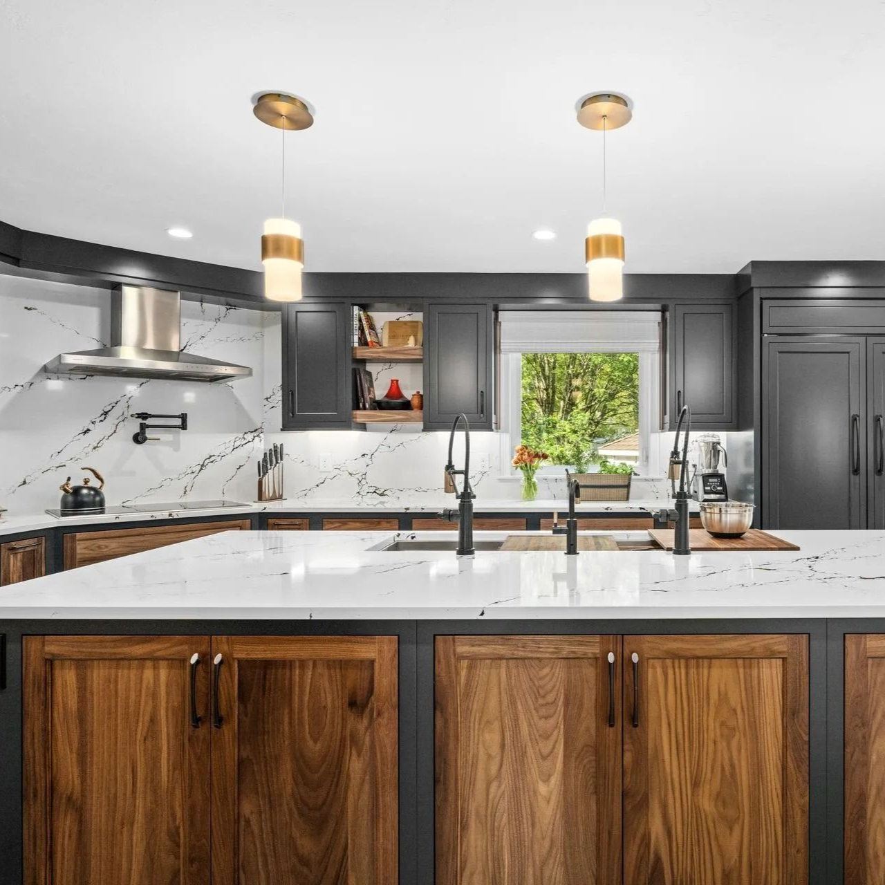 Modern kitchen with dark cabinetry, wood island, white countertops, and gold pendant lights.