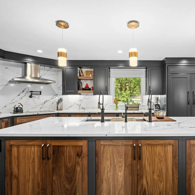 Modern kitchen with dark cabinetry, wood island, white countertops, and gold pendant lights.