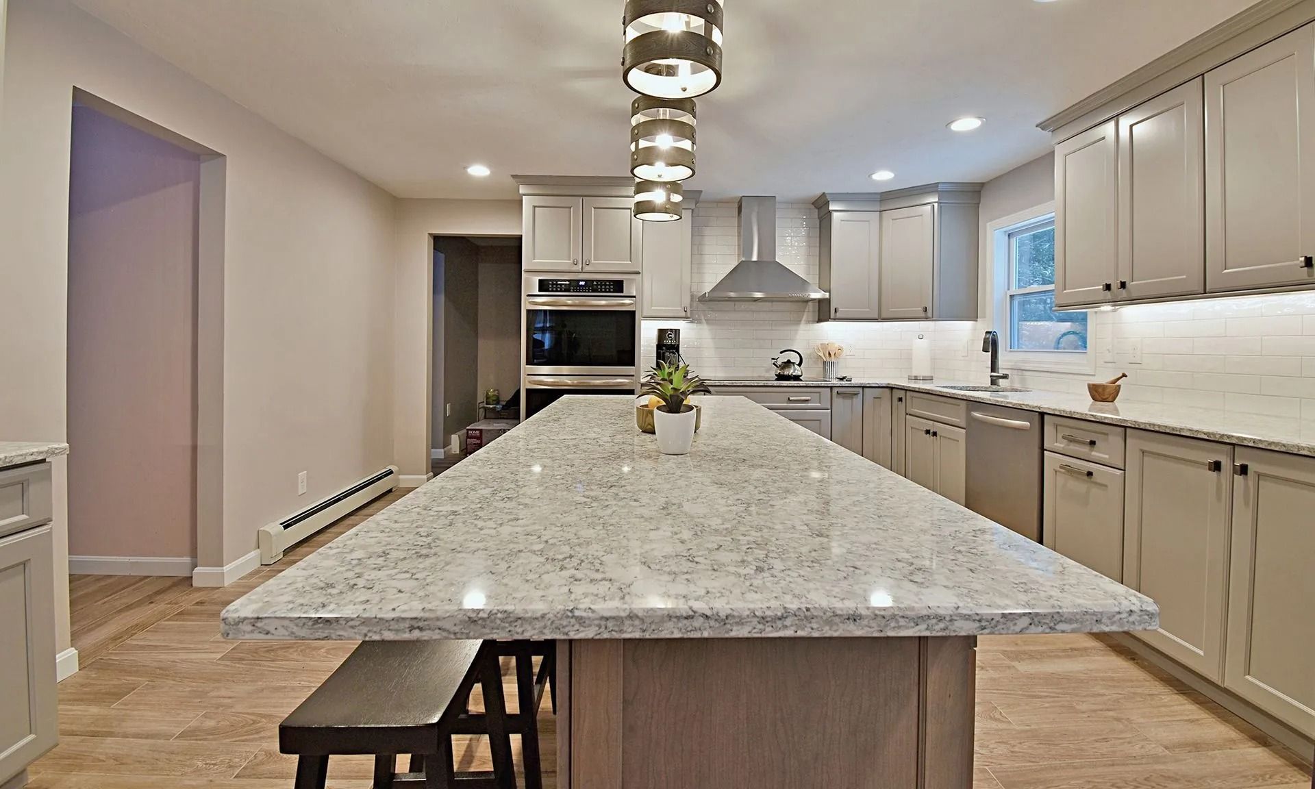 Modern kitchen with a gray island, cabinets, and stainless steel appliances.