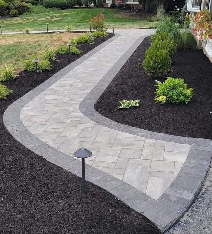 A stone path leading to a yellow house in a garden.