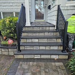 Front steps of a house with black railings and gray pavers