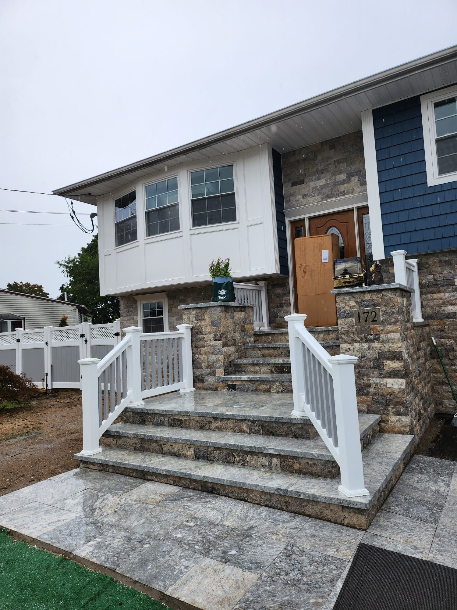 Front view of a stone house with white railings, steps, and a wooden door 