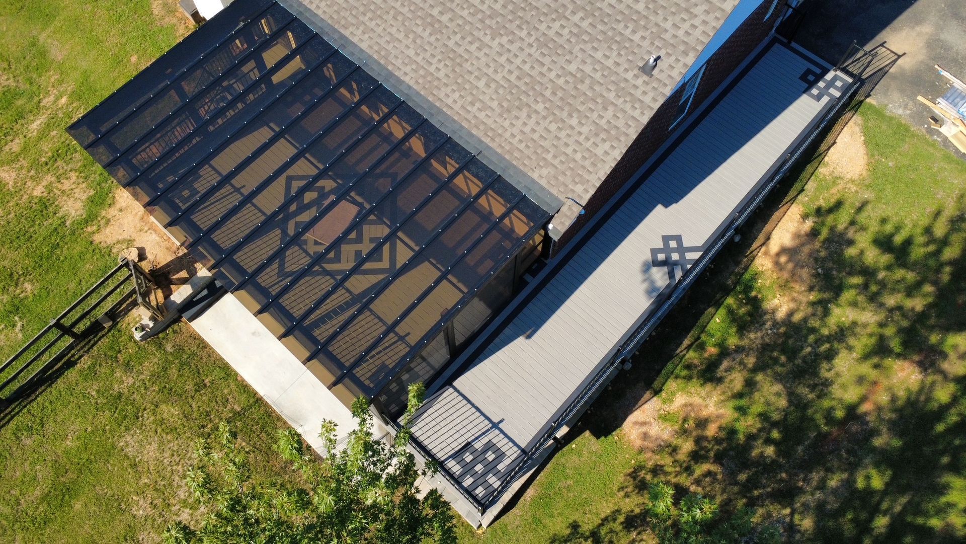 Aerial view of a building roof with a large black solar panel array beside a gray rooftop section.