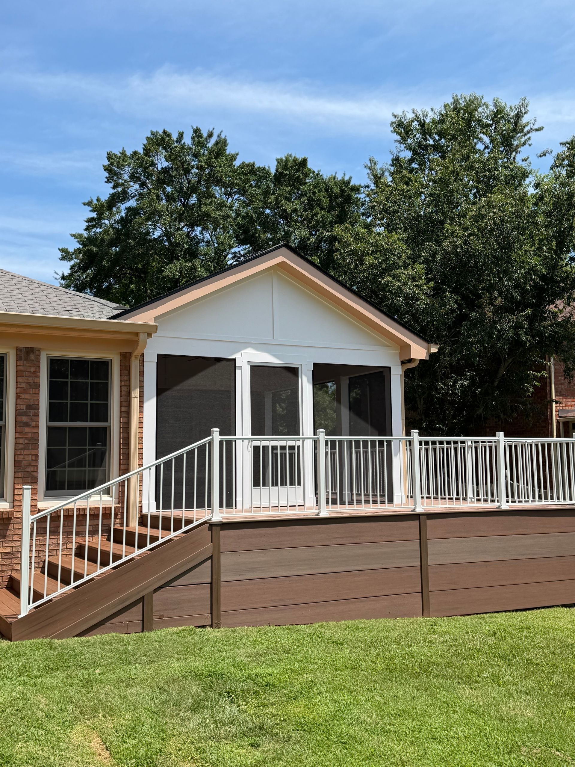 Back porch with white railing, screened gazebo, and wooden ramp in a grassy backyard