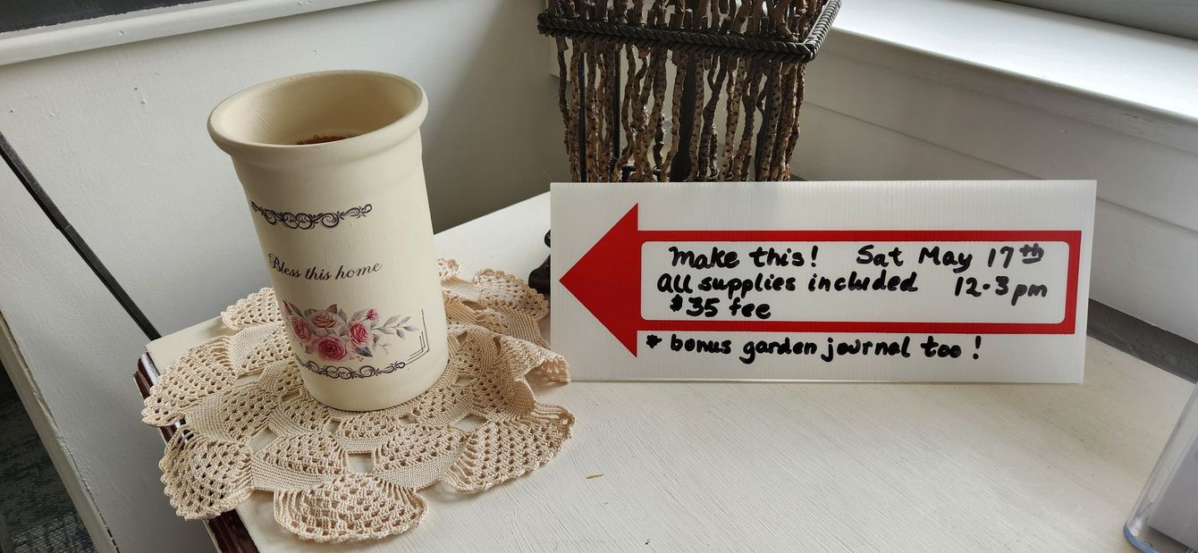 A vase sits on a table next to a sign that says Saturday May 17th