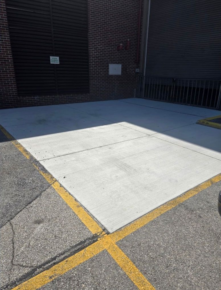 A gravel-filled loading dock with yellow painted edges and a brick wall in the background - after