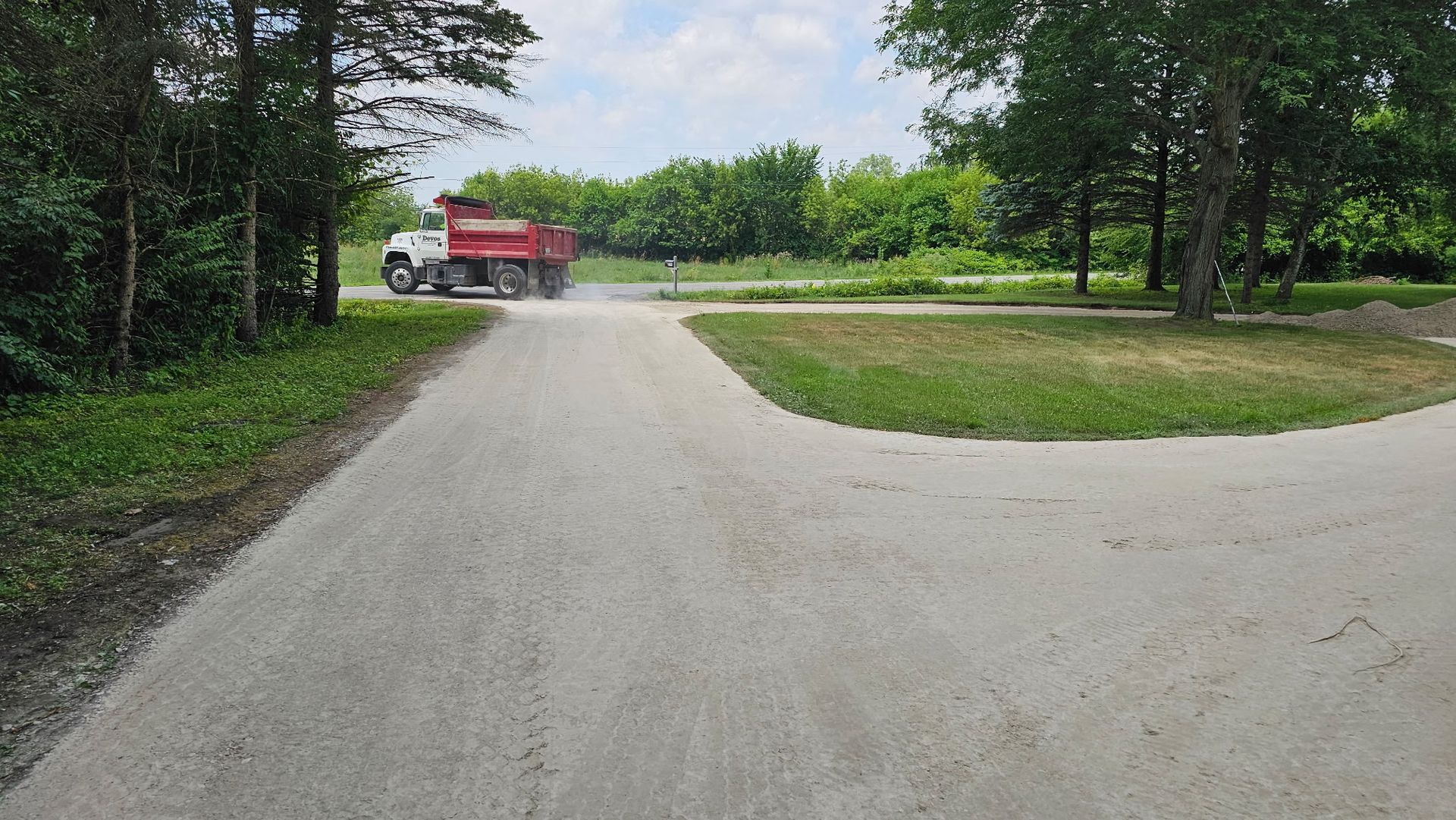 A red dump truck is driving down a dirt road.