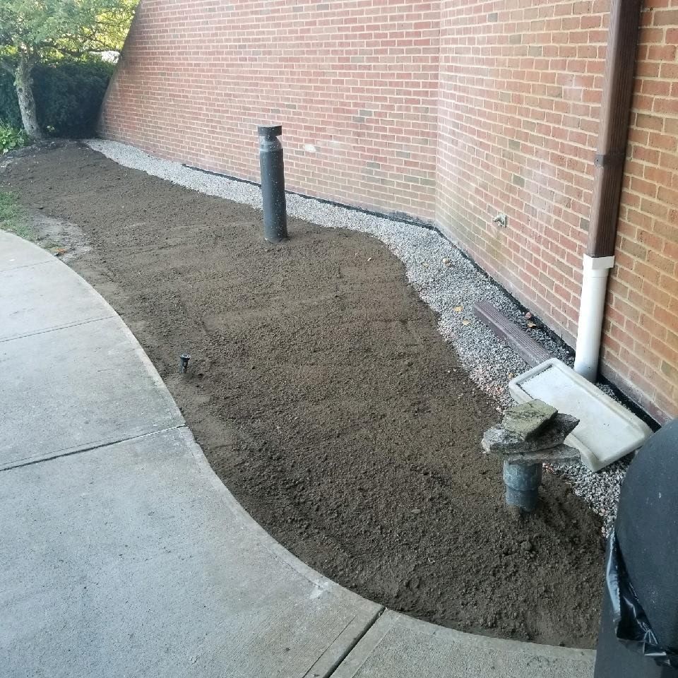 A sidewalk next to a brick wall with a lot of dirt on it