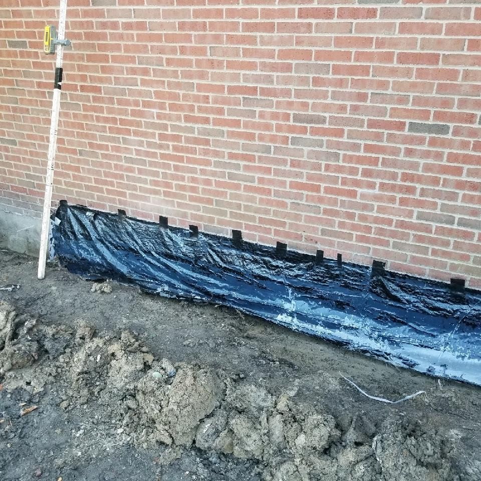A brick wall with a black tarp covering it.