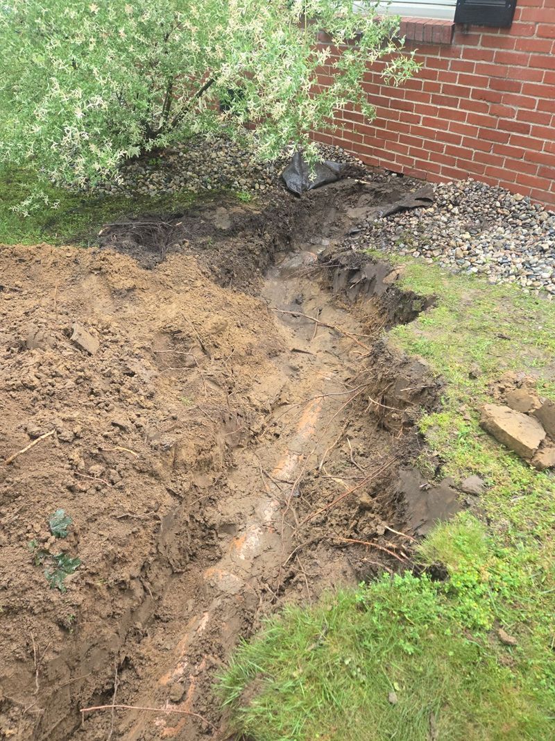 A large pile of dirt is sitting in front of a brick building.