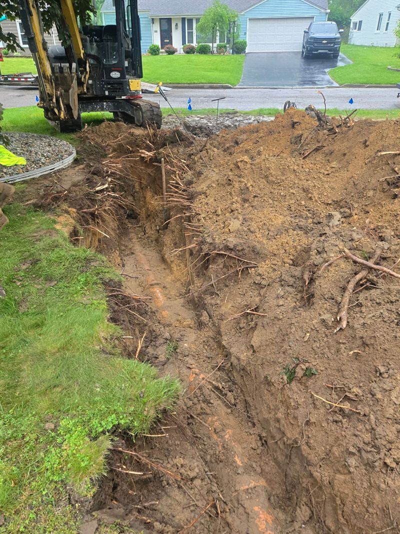 A bulldozer is digging a hole in the ground in front of a house.